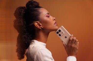 1. Mulher com cabelo enrolado segurando smartphone motorola com câmera tripla e design elegante.