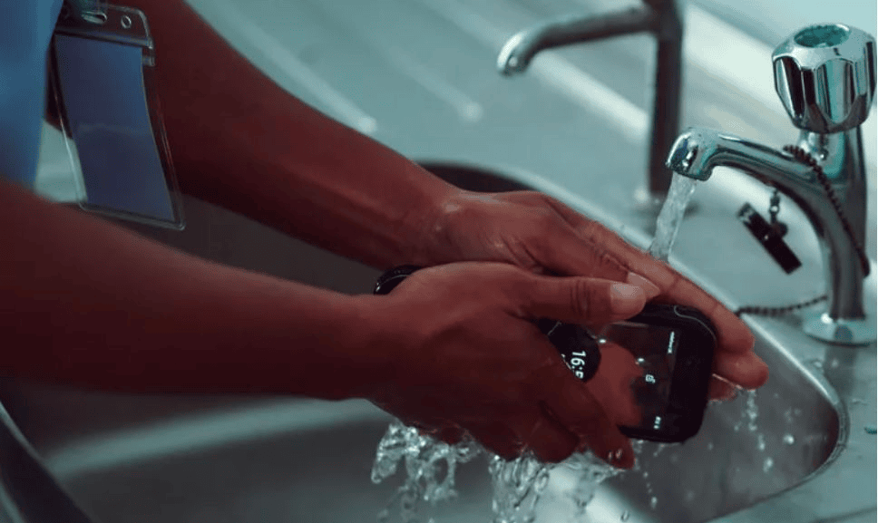 Tecnologia e smartphone em uso durante lavagem de mãos.