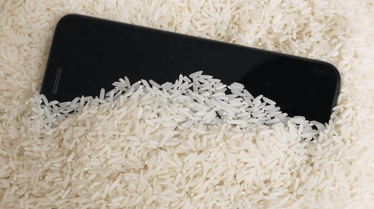 Celular com arroz para secar, técnica de recuperação de dispositivos eletrônicos danificados por água.