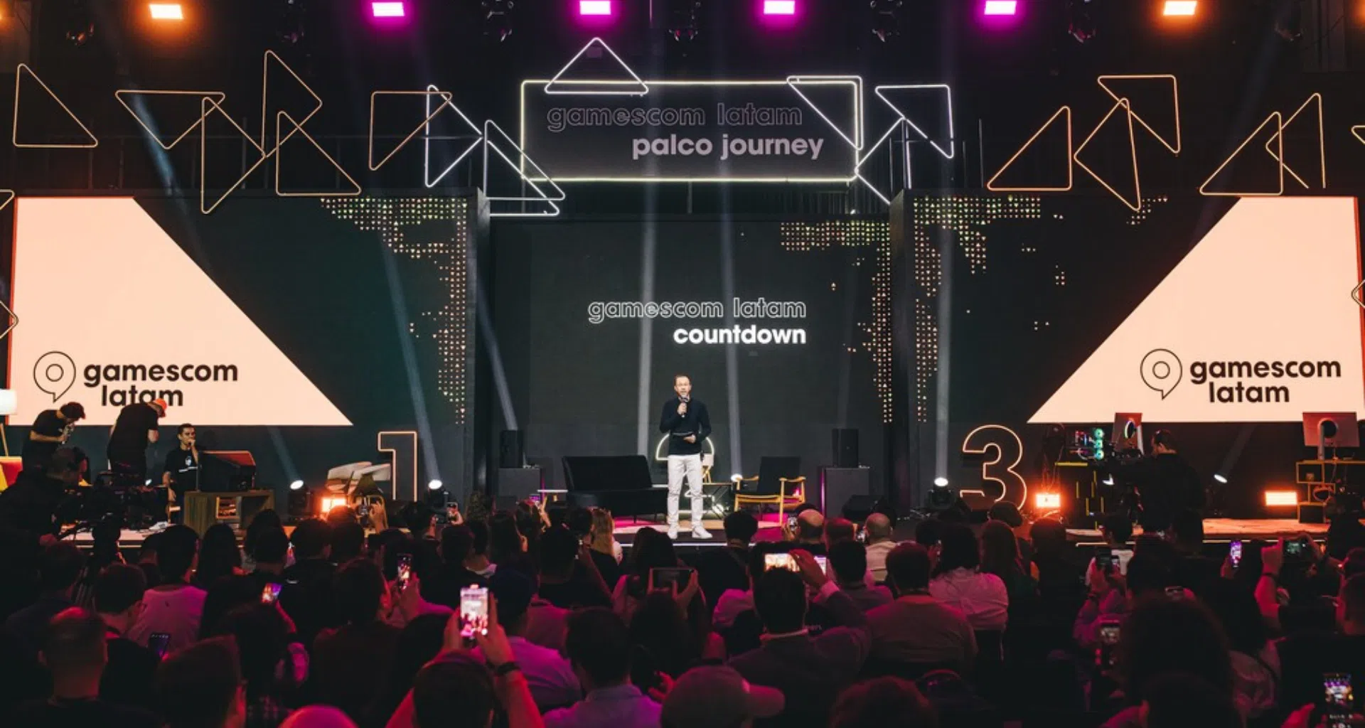 Apresentação de evento de games com palco iluminado e público assistindo na gamerscom latam.