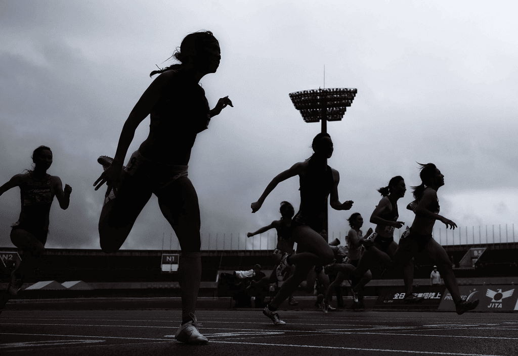 Atletas femininas correndo na pista em competição de atletismo, esportes ao ar livre, evento esportivo.