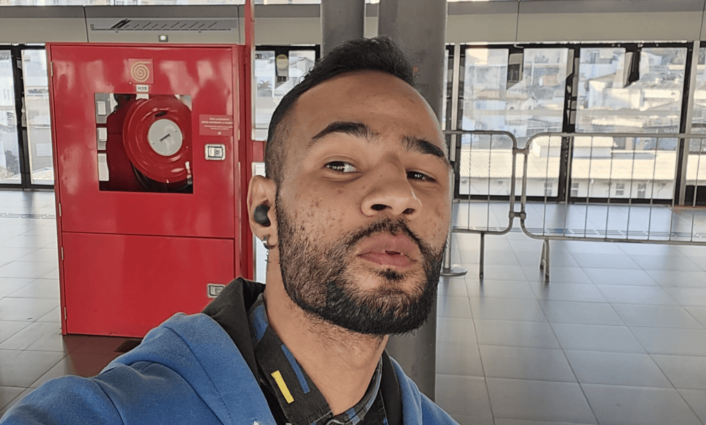 1. Homem com fone de ouvido em embarque no aeroporto ao lado de extintor de incêndio vermelho.
