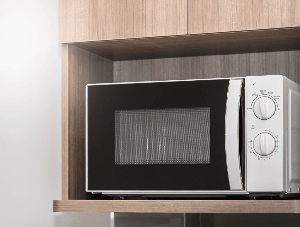 Microondas moderno de inox em cozinha com móveis de madeira, tecnologia e inovação.