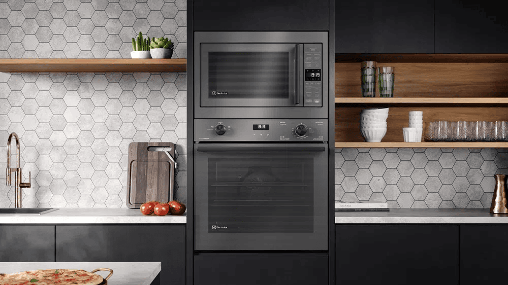 Micro-ondas e forno elétrico embutidos na cozinha moderna com revestimento hexagonal.
