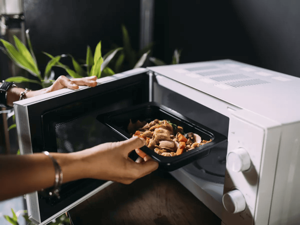 Comida sendo aquecida em micro-ondas, cozinha prática, aquecimento de alimentos, eletrodomésticos modernos, refeições rápidas.