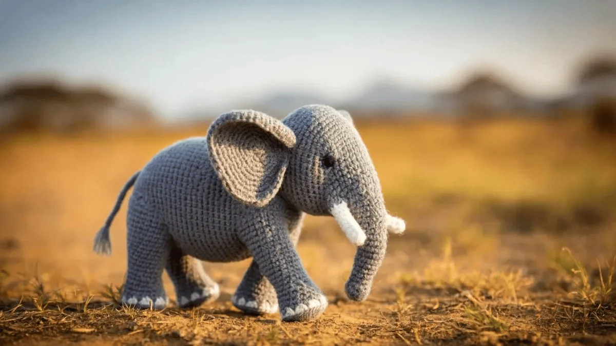 Elefante de tricô em campo de terra, artesanato criativo e decorativo, presente artesanal, brinquedo de crochê fofo.