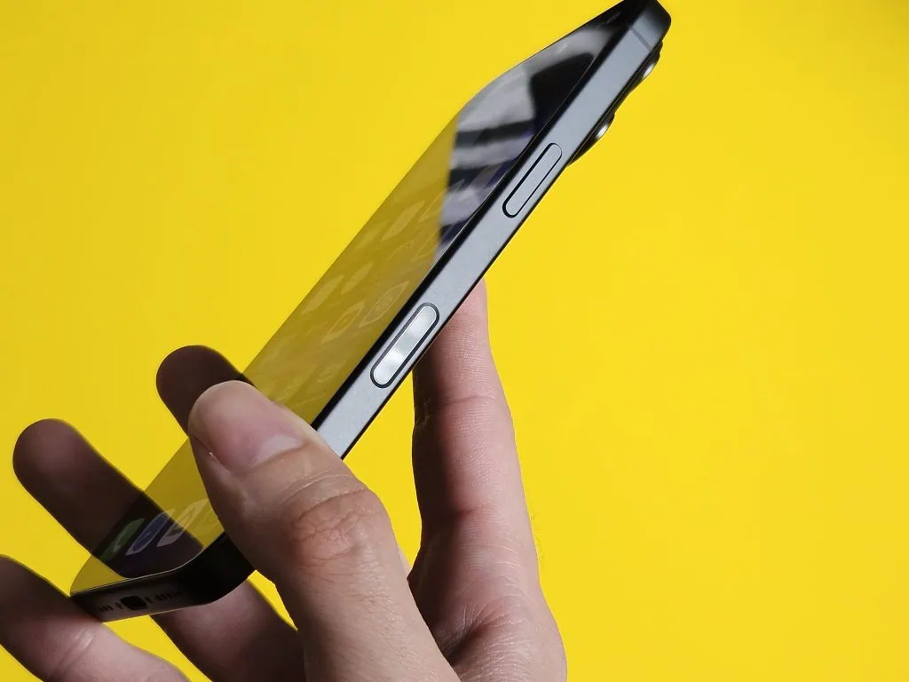 Anmeldelse: iPhone 16, hjemmehørende i en tidsalder av kunstig intelligens Smarttelefonskjerm som fremhever sidene og knappene, på en livlig gul bakgrunn.