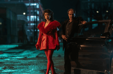 Moderna mulher com vestido vermelho e homem ao lado de carro na rua à noite, cena de filme ou série.