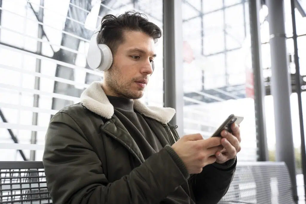 Melhores fones de ouvido com cancelamento de ruído de 2025 Homem usando headphone sem fio conectado ao smartphone
