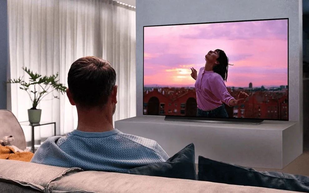 1. Homem assistindo tv de alta definição com imagem vibrante e cores realistas.