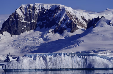 Picos cobertos de neve na antartica, e um iceberg na frente