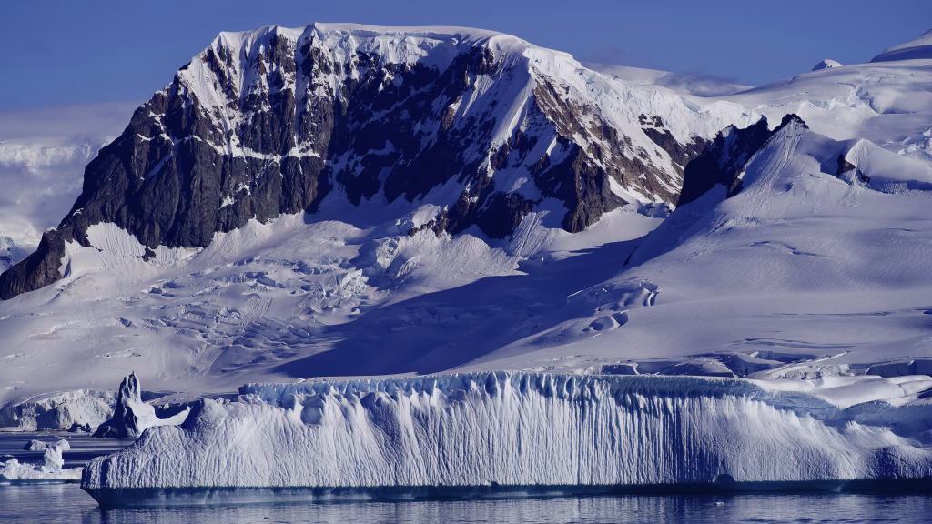 Aventuras na antartica: uma viagem de descobertas Pico coberto de neve na antartica, e um iceberg na frente