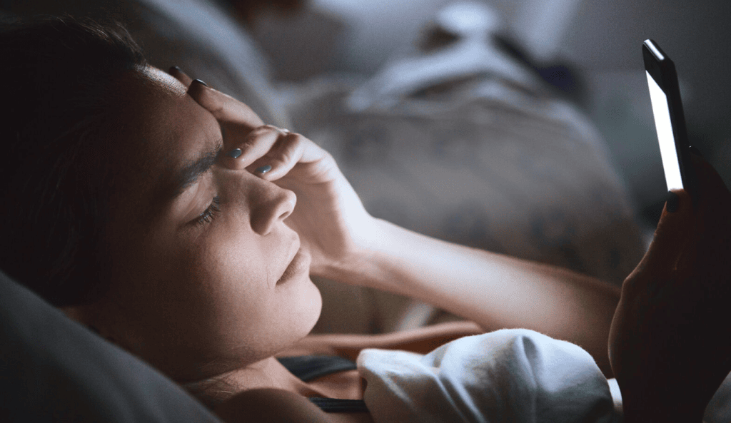 Cansaço ao usar smartphone, pessoa deitada na cama, rotina digital, excesso de uso de tecnologia, saúde e bem-estar.
