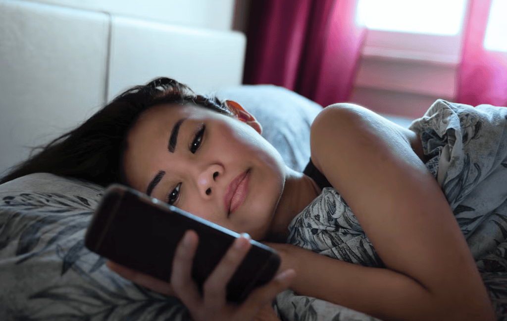 Pessoa relaxando na cama usando smartphone, tecnologia, entretenimento, redes sociais, conforto, vazia, digital, descanco, lazer, mulher jovem, noite.