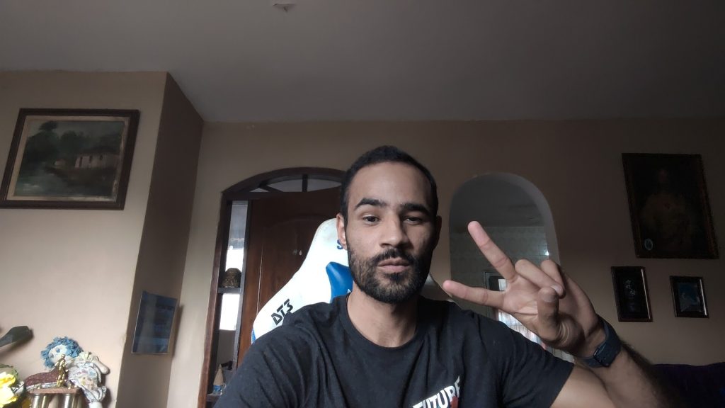 1. Jovem fazendo sinal de paz com mãos em ambiente interno com decoração clássica.