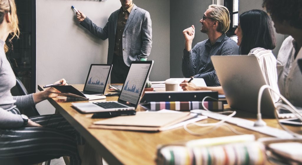 Reunião de equipe com apresentação de dados e análises em sala de escritório moderna, focada em tecnologia, inovação e produtividade.