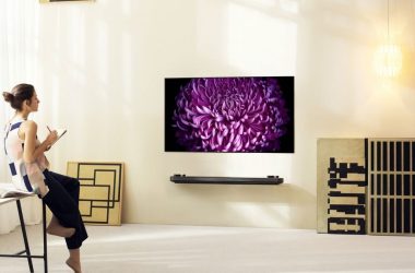 Mulher anotando enquanto olha pra tv