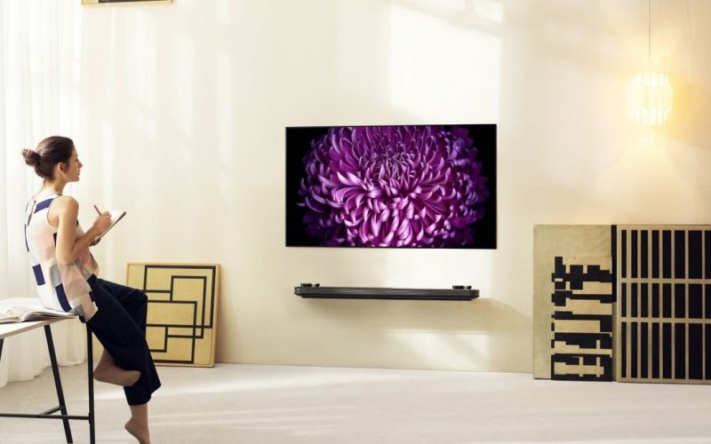 Mulher anotando enquanto olha pra tv