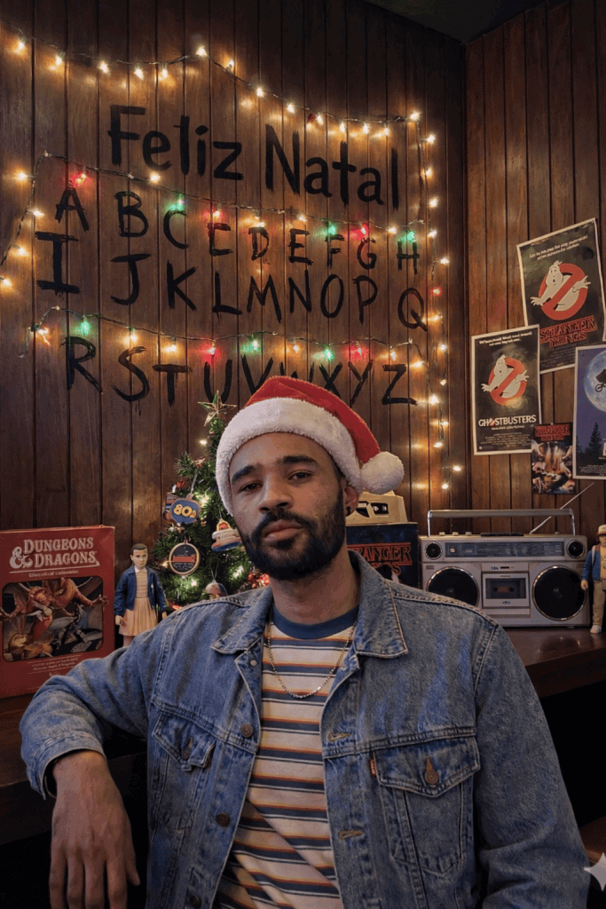 Imagem de homem com touca de papai noel em ambiente natalino.