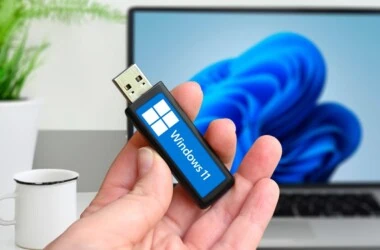 Man holding a USB drive with the Windows 11 logo.
