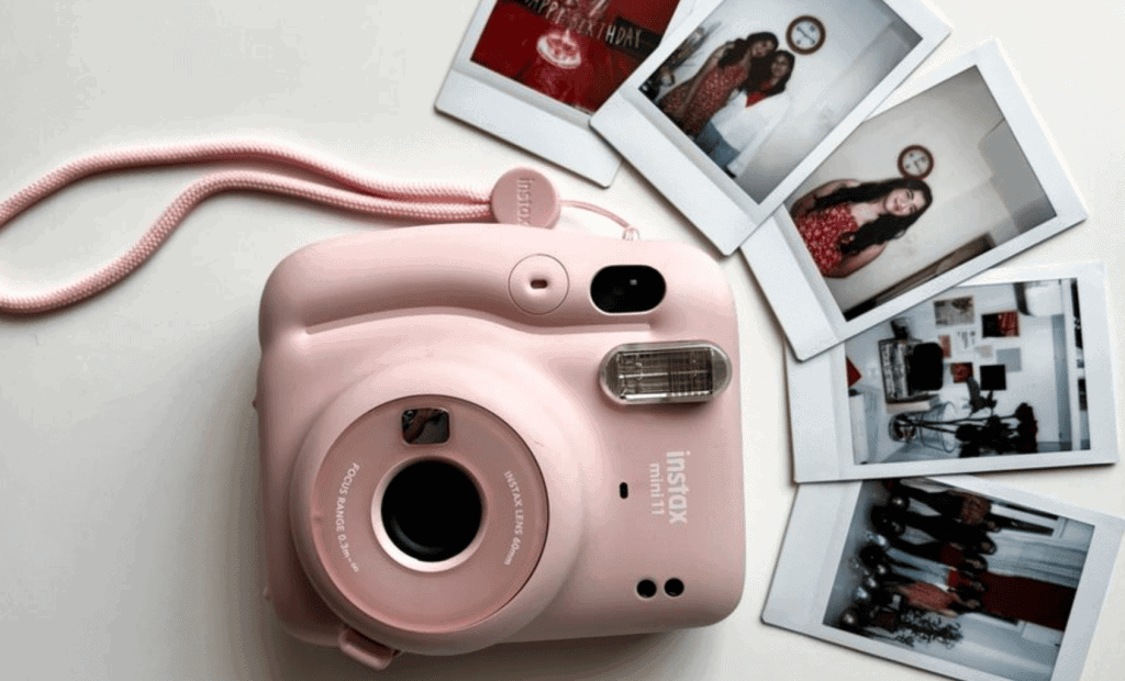 Câmera instantânea rosa ao lado de fotos impressas, ideal para fotos rápidas e divertidas.