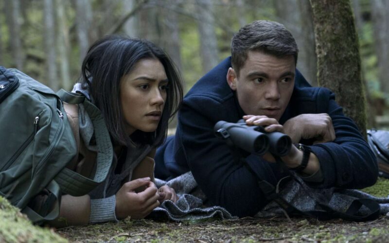 Imagem de dois jovens observando pelo binóculo na floresta.