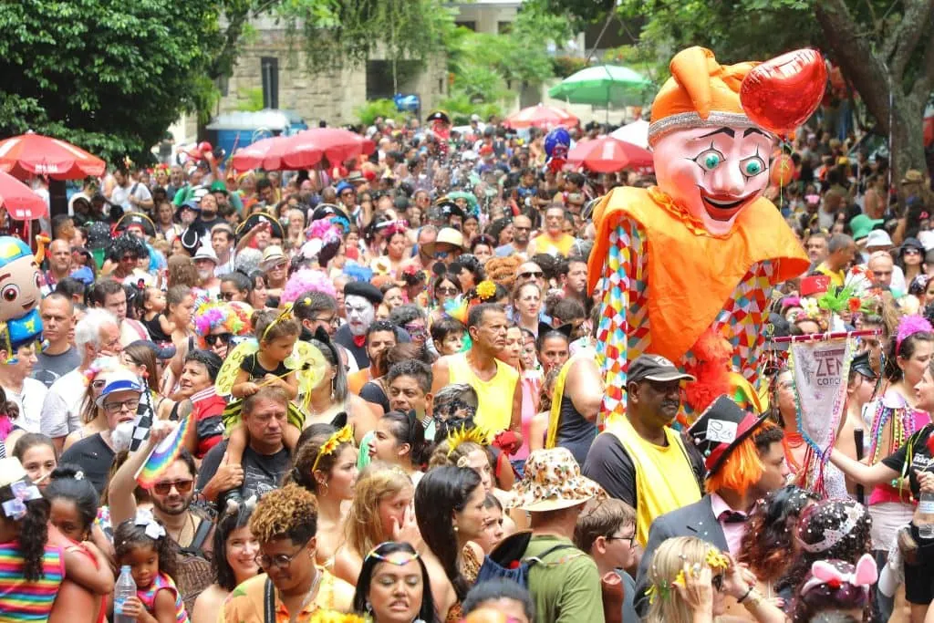 Carnaval 2026: confira a agenda de blocos de rua, desfiles e trios elétricos pelo brasil Multidão no carnaval de rua com boneco gigante e foliões com fantasias coloridas.