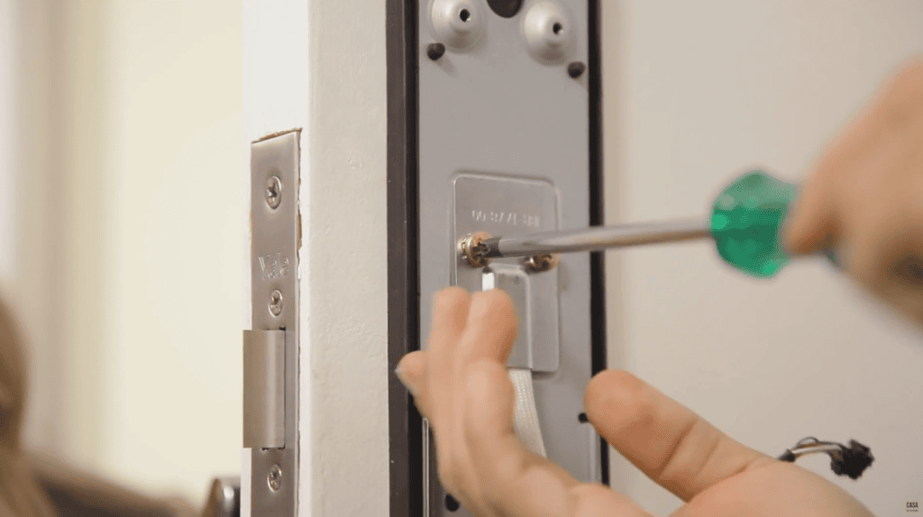 Melhores fechaduras digitais para comprar para sua casa Fechadura digital sendo instalada na porta com ferramenta.