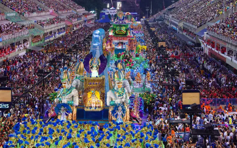 Rei de carnaval e foliões na avenida durante desfile de rua.