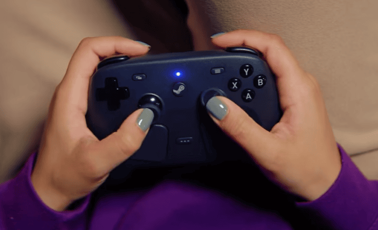 Pessoa segurando o steam controller da valve visto de cima, com layout de botões e analógicos visíveis