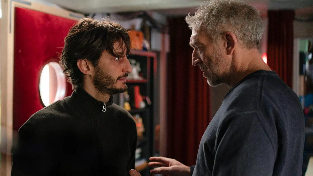 Dois homens de perfil conversando em cena