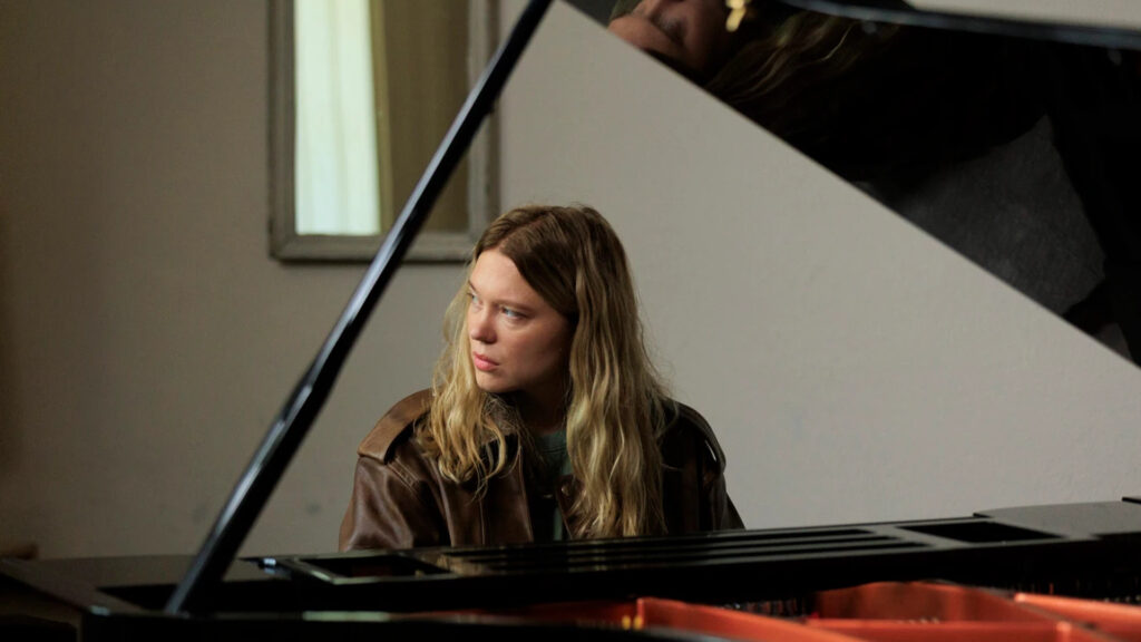 Cena da atriz lea seydoux olhado para a esquerda enquanto toca piano