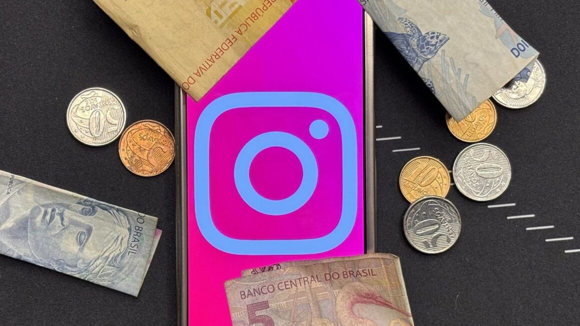Celular com o logo do instagram cercado por cédulas e moedas de real brasileiro, representando a assinatura paga instagram plus.