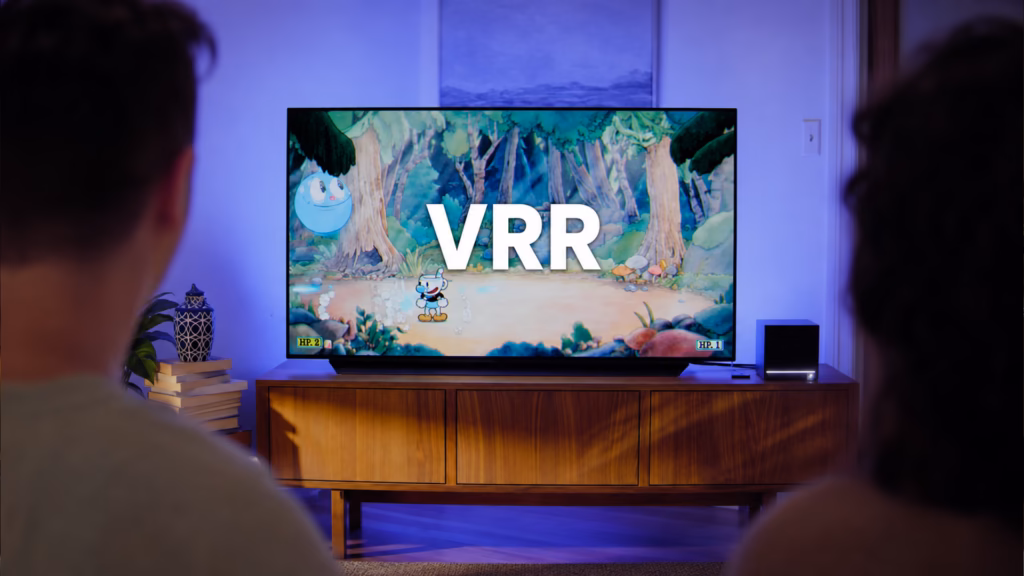 O que é vrr: entenda a taxa de atualização variável em monitores e tvs Duas pessoas diante de uma tv oled assistindo ao jogo cuphead com o texto vrr centralizado, mostrando na prática o que é vrr aplicado a consoles e televisores modernos.