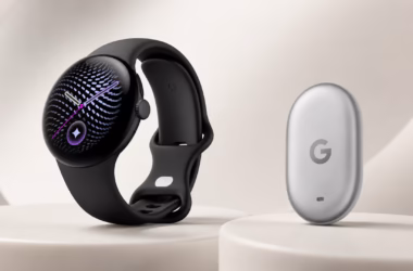 Smartwatch preto com mostrador circular exibindo ponteiros roxos ao lado do pixel tag prateado da google.