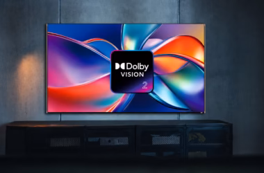Smart tv exibindo o logo dolby vision 2 sobre formas coloridas abstratas em uma sala escura.