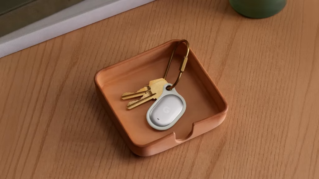 Google lança pixel watch 5 e pixel tag no made by google 2026 Pixel tag branco preso a um chaveiro com duas chaves, dentro de uma bandeja sobre uma mesa de madeira.