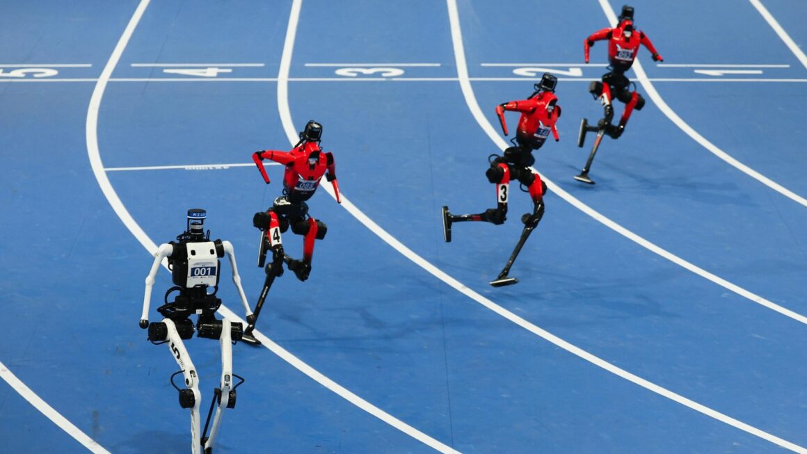 Cinco robôs humanoides correm em uma pista azul durante competição em pequim