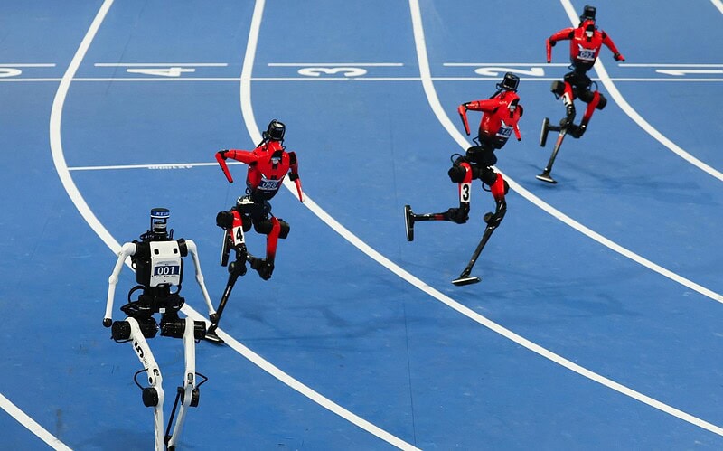 Cinco robôs humanoides correm em uma pista azul durante competição em pequim
